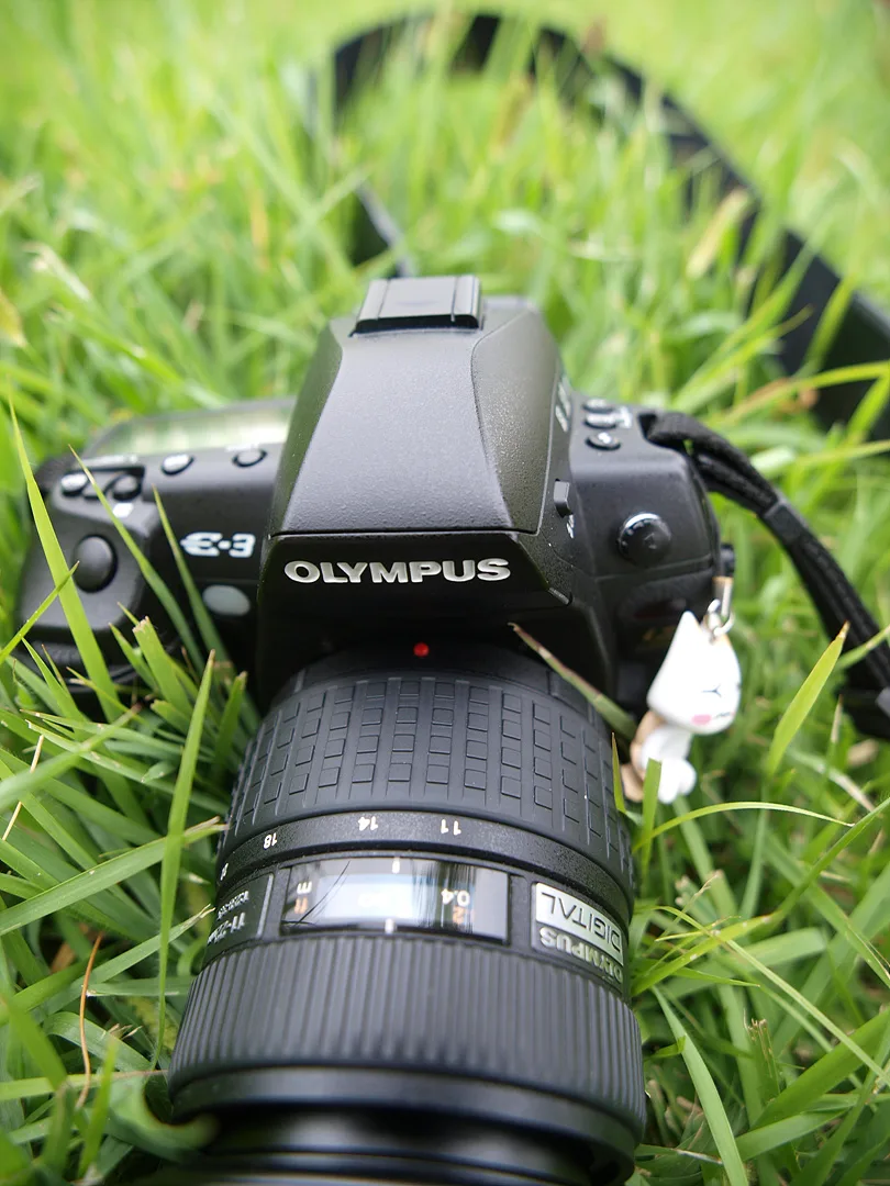 푸른 잔디 위에 놓인 올림푸스 DSLR 카메라 · 2009-09-06